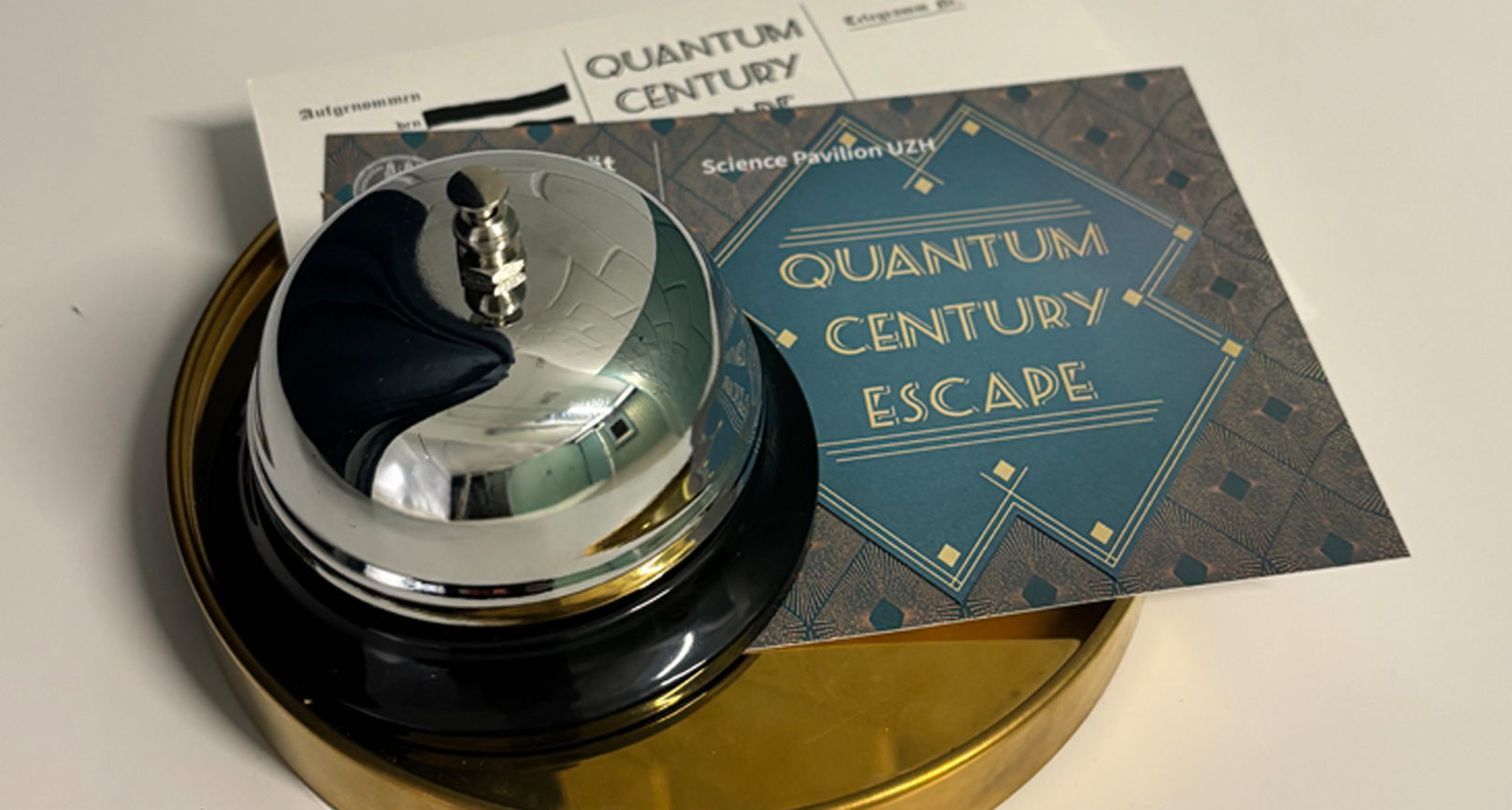 A table bell and an quantum century escape room flyer on a round tray.