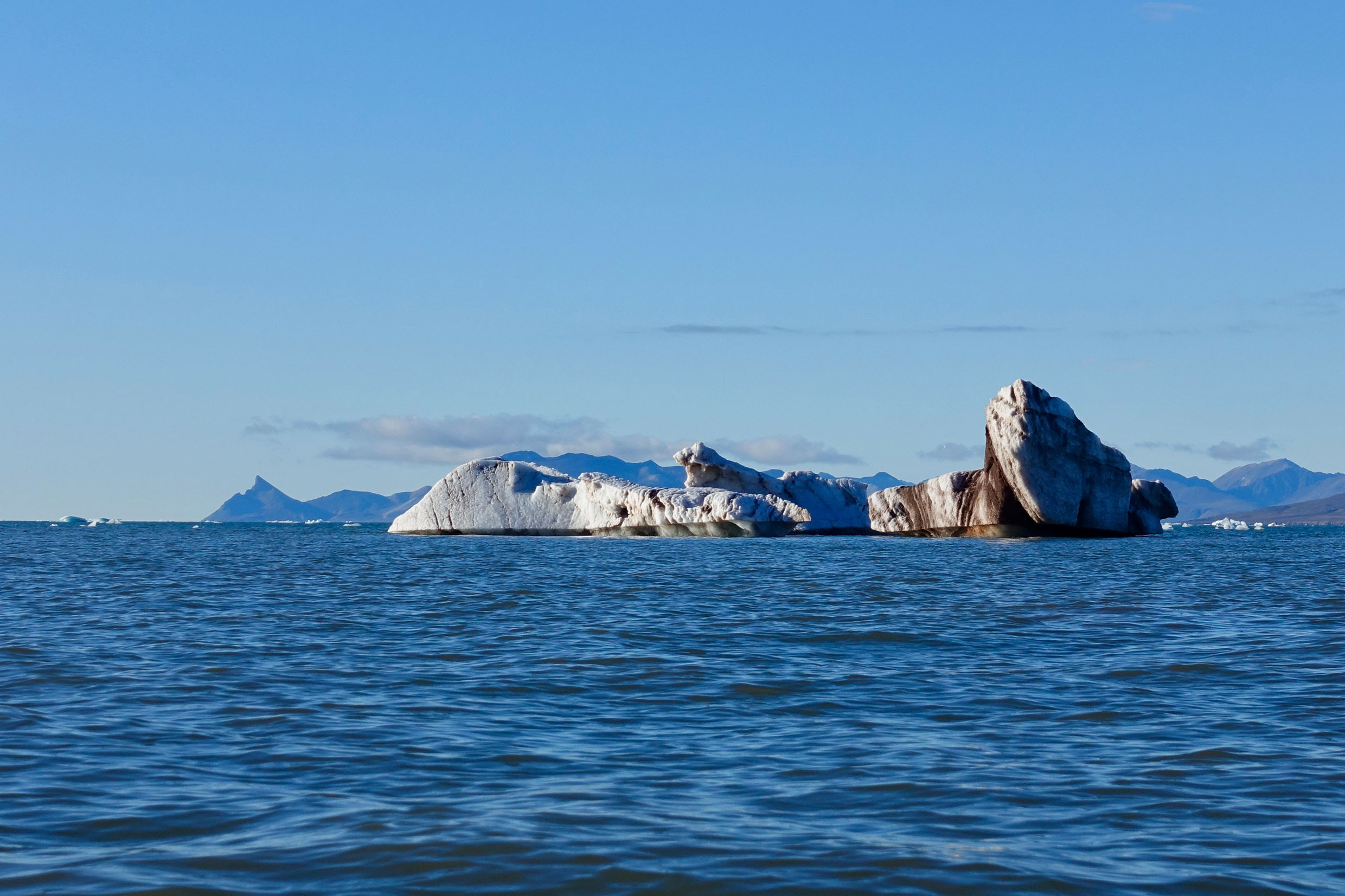 Eisberg im Meer mit Bergen im Hintergrund