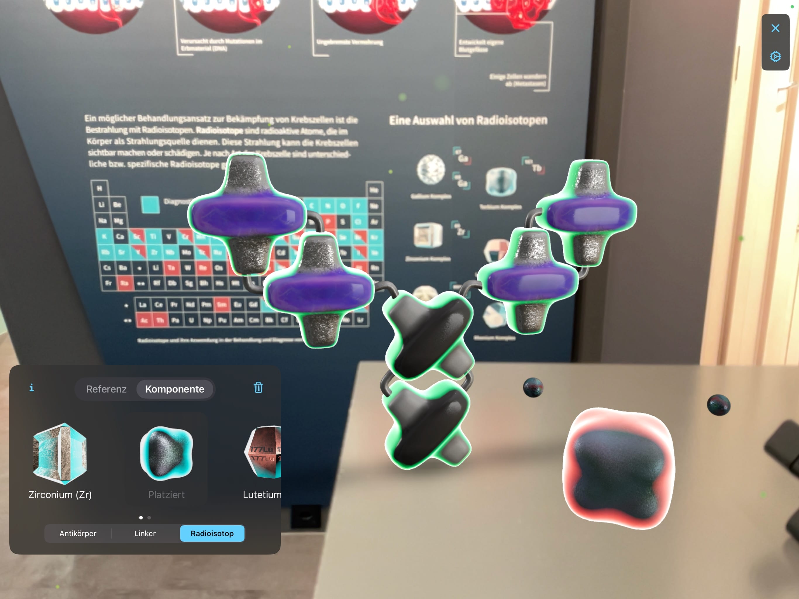 Molekül und Radioisotop mit AR auf einem Tisch platziert mit der Radiotracer-Ausstellung im Hintergrund